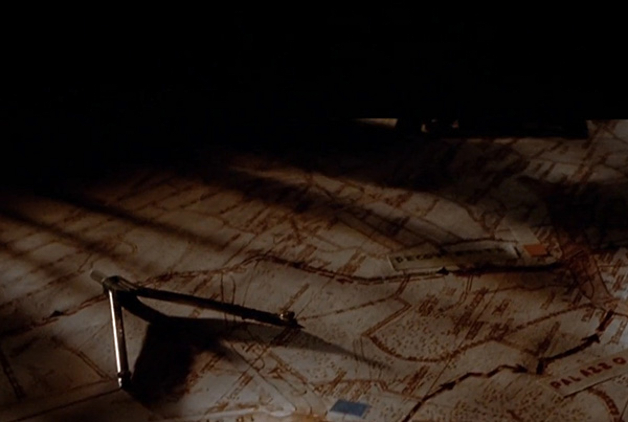 Hand-drawn map spread across a table under raking light, from the title sequence of The Italian Job