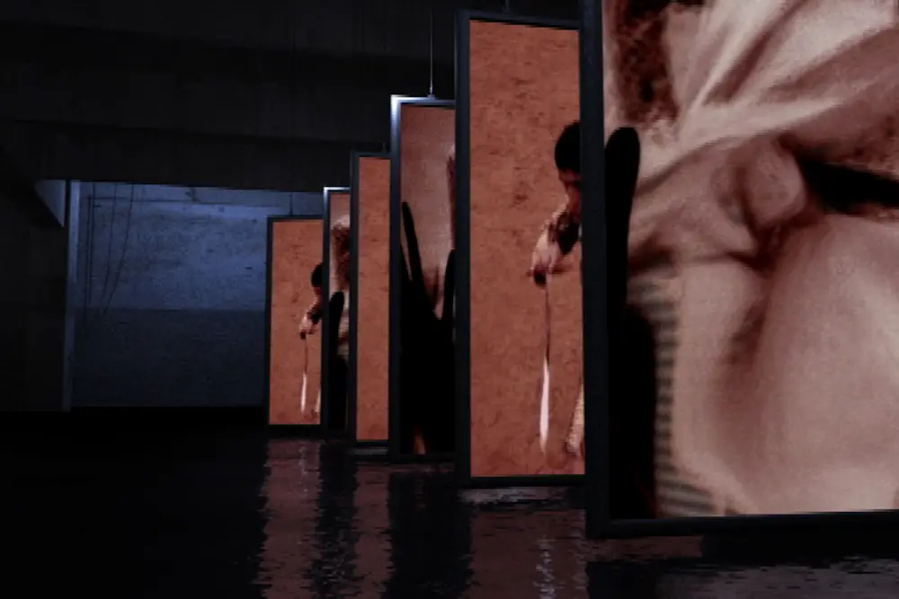 Corridor of hanging screens receding into the hall